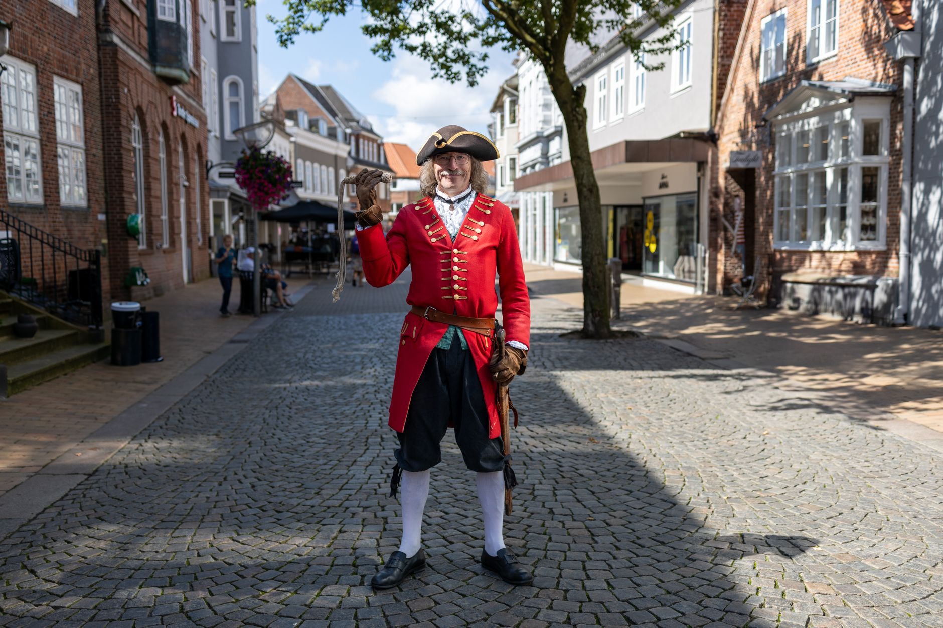 Town crier in traditional costume ringing a bell in an English market square, illustrating town crier history
